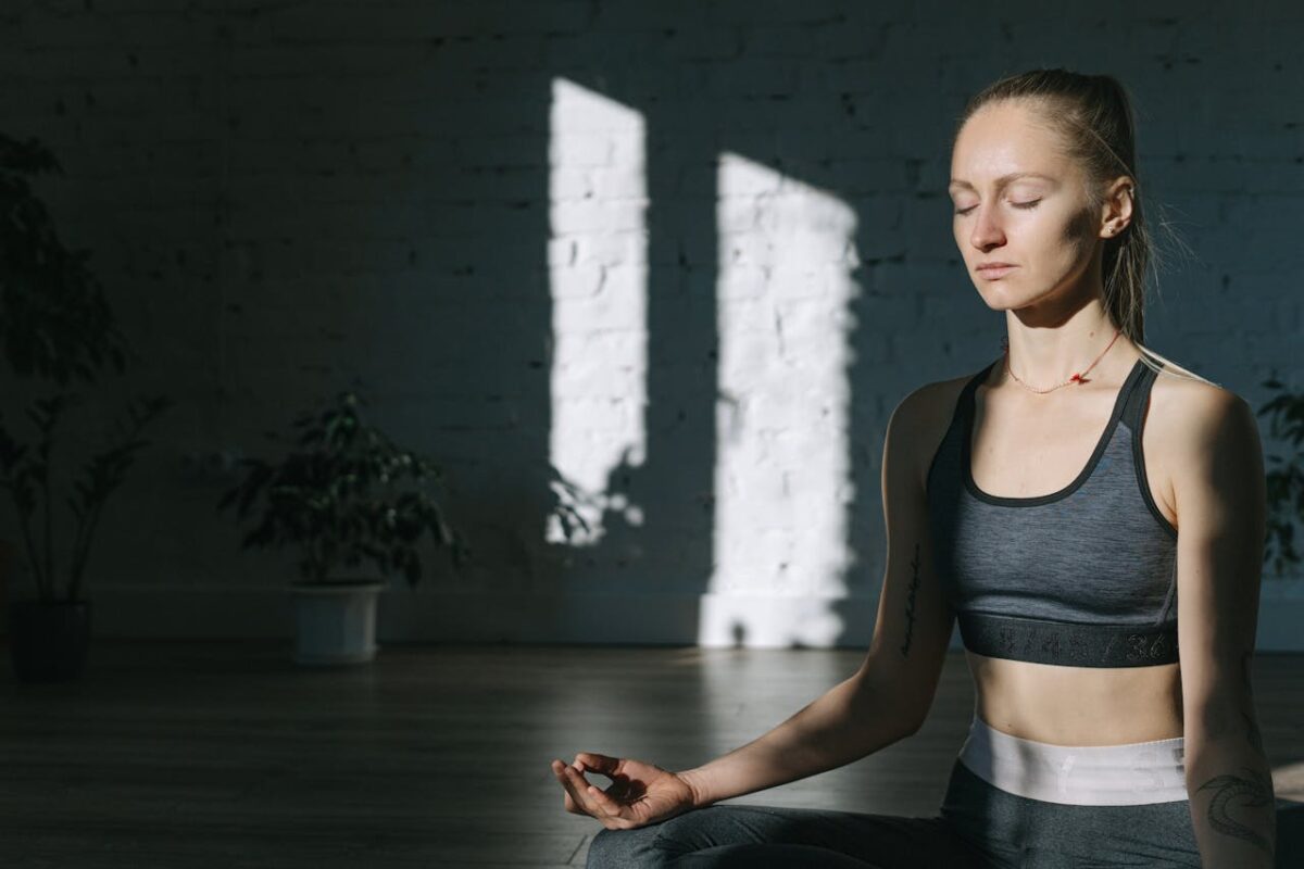 approach-img A woman meditates indoors in a serene yoga session, embracing mindfulness and tranquility.